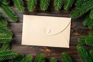 Top view of envelope decorated with a frame made of fir tree on wooden background. New Year time concept photo