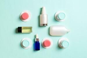 Group of small bottles for travelling on colored background. Copy space for your ideas. Flat lay composition of cosmetic products. Top view of cream containers with cotton pads photo