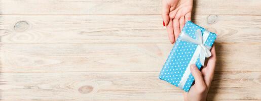 Top view of a man and a woman holding a gift box on wooden background. Love and relationship concept. Copy space photo