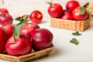 Ripe garden apple fruits with leaves in basket on wooden table. Top view flat lay with copy space photo