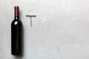 One Bottle of red wine with corkscrew on colored table. Flat lay, top view wth copy space photo