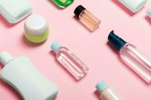 Top view of cosmetic containers, sprays, jars and bottles on pink background. Close-up view with empty space for your design photo