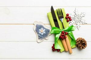 Top view of New Year dinner on wooden background. Festive cutlery on napkin with christmas decorations and toys. Family holiday concept with copy space photo