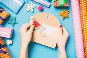 Top view of woman holding an envelope on blue background made of holiday decorations. Christmas time concept photo