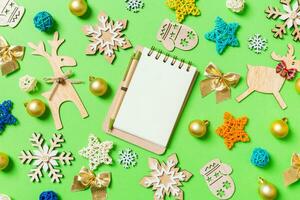 Top view of notebook on green background with New Year toys and decorations. Christmas time concept photo