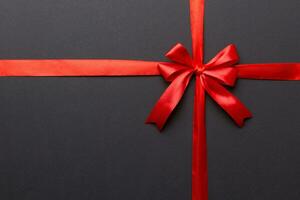 Top view of Red ribbon rolled and red bow isolated on colored background. Flat lay with copy space photo