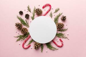 Flat lay Christmas composition. Round Paper blank, pine tree branches, christmas decorations on Colored background. Top view, copy space for text photo