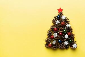 Christmas tree made from natural cones on colored background, view from above. New Year minimal concept with copy space photo