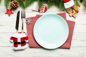 Top view of Christmas dinner on wooden background. Plate, utensil, fir tree and holiday decorations with copy space. New Year time concept photo