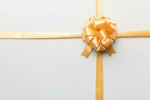 Top view of gold ribbon rolled and yellowbow isolated on colored background. Flat lay with copy space photo