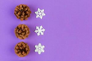 Top view of holiday composition made of pine cones and white snowflakes on colorful background. Winter time and Christmas concept with copy space photo