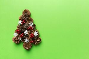 Christmas tree made from natural cones on colored background, view from above. New Year minimal concept with copy space photo
