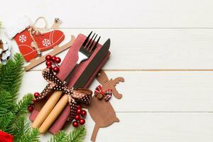 Top view of holiday objects on wooden background. Utensils tied up with ribbon on napkin. Christmas decorations and reindeer with copy space. New year dinner concept photo