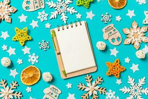 Top view of notebook on blue background with New Year toys and decorations. Christmas time concept photo