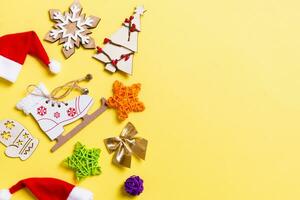 Top view of Christmas decorations and Santa hats on yellow background. Happy holiday concept with copy space photo