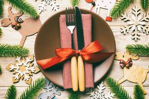 vista superior de cubiertos y platos sobre fondo de madera festiva. concepto de cena familiar de año nuevo. abeto y adornos navideños foto