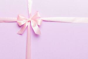 Top view of purple ribbon rolled and pink bow isolated on colored background. Flat lay with copy space photo