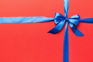 Top view of blue ribbon rolled and blue bow isolated on colored background. Flat lay with copy space photo