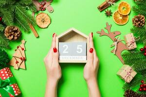 Top view of female hands holding calendar on green background. The twenty fifth of December. Holiday decorations. Christmas time concept photo