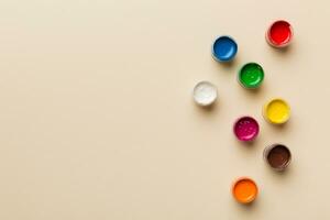 jars with gouache of different colors on Colored background. hobby painting. Top view with empty space. workplace for creativity. home teaching concept drawing photo