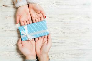 Top view of a couple congratulating each other on wooden background. Giving a present. Festive concept. Copy space photo