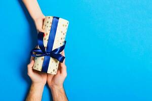 Top view of couple giving and receiving a gift on colorful background. Romantic concept with copy space photo