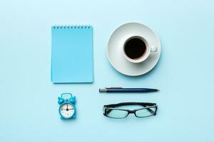 Modern office desk table with notebook and other supplies with cup of coffee. Blank notebook page for you design. Top view, flat lay photo