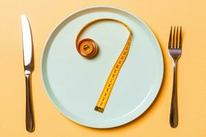 Question mark made of measuring tape on round plate on orange background. Top view of hesitation and diet concept photo