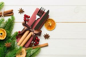 Top view of utensils on festive napkin on wooden background. Christmas decorations with dried fruits and cinnamon. New year dinner concept with copy space photo