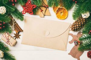 Top view of fir tree branches, envelope and festive decorative toys on wooden background. New Year time concept photo