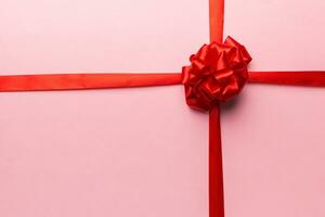 Top view of Red ribbon rolled and red bow isolated on colored background. Flat lay with copy space photo