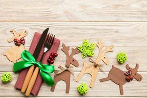 New year set of fork and knife on napkin. Top view of christmas decorations and reindeer on wooden background. Holiday family dinner concept with empty space for your design photo