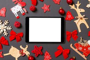 Christmas black background with holiday toys and decorations. Top view of digital tablet. Happy New Year concept photo