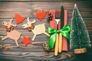 New year set of fork and knife on napkin. Top view of christmas decorations and reindeer on wooden background. Close up of holiday family dinner concept photo