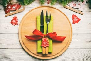 vista superior de cubiertos y platos sobre fondo de madera festiva. concepto de cena familiar de año nuevo. abeto y adornos navideños foto