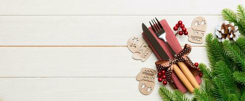 parte superior ver bandera de Navidad decoraciones en de madera antecedentes. tenedor y cuchillo en servilleta atado arriba con cinta y vacío espacio para tu diseño. nuevo año modelo concepto foto