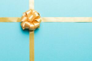 Top view of gold ribbon rolled and yellowbow isolated on colored background. Flat lay with copy space photo