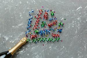 Creative flat lay composition with bottle of champagne and space for text on color background. Champagne bottle with colorful party streamers. holiday or christmas concept photo