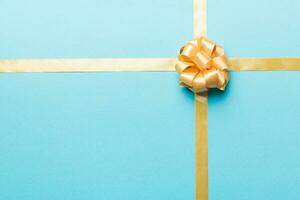 Top view of gold ribbon rolled and yellowbow isolated on colored background. Flat lay with copy space photo