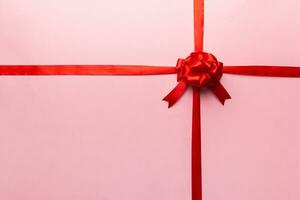 Top view of Red ribbon rolled and red bow isolated on colored background. Flat lay with copy space photo