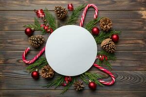 Flat lay Christmas composition. Round Paper blank, pine tree branches, christmas decorations on Colored background. Top view, copy space for text photo