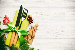 vista superior de tenedor y cuchillo en servilleta con adornos navideños y árbol de año nuevo sobre fondo de madera. vacaciones y concepto festivo con espacio de copia foto