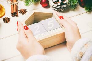 Top view of female hands holding a calendar on wooden background. The twenty fifth of December. Holiday decorations. Christmas concept photo