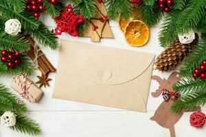 Top view of fir tree branches, envelope and festive decorative toys on wooden background. New Year time concept photo