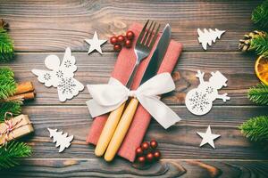 Top view of utensils on festive napkin on wooden background. Christmas decorations with dried fruits and cinnamon. Close up of New year dinner concept photo