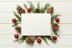 Flat lay Christmas composition. square Paper blank, pine tree branches, christmas decorations on Colored background. Top view, copy space for text photo