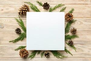 Flat lay Christmas composition. square Paper blank, pine tree branches, christmas decorations on Colored background. Top view, copy space for text photo