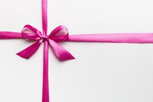 Top view of purple ribbon rolled and pink bow isolated on colored background. Flat lay with copy space photo