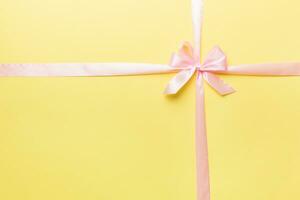 Top view of purple ribbon rolled and pink bow isolated on colored background. Flat lay with copy space photo