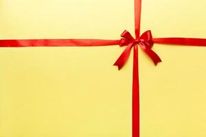 Top view of Red ribbon rolled and red bow isolated on colored background. Flat lay with copy space photo